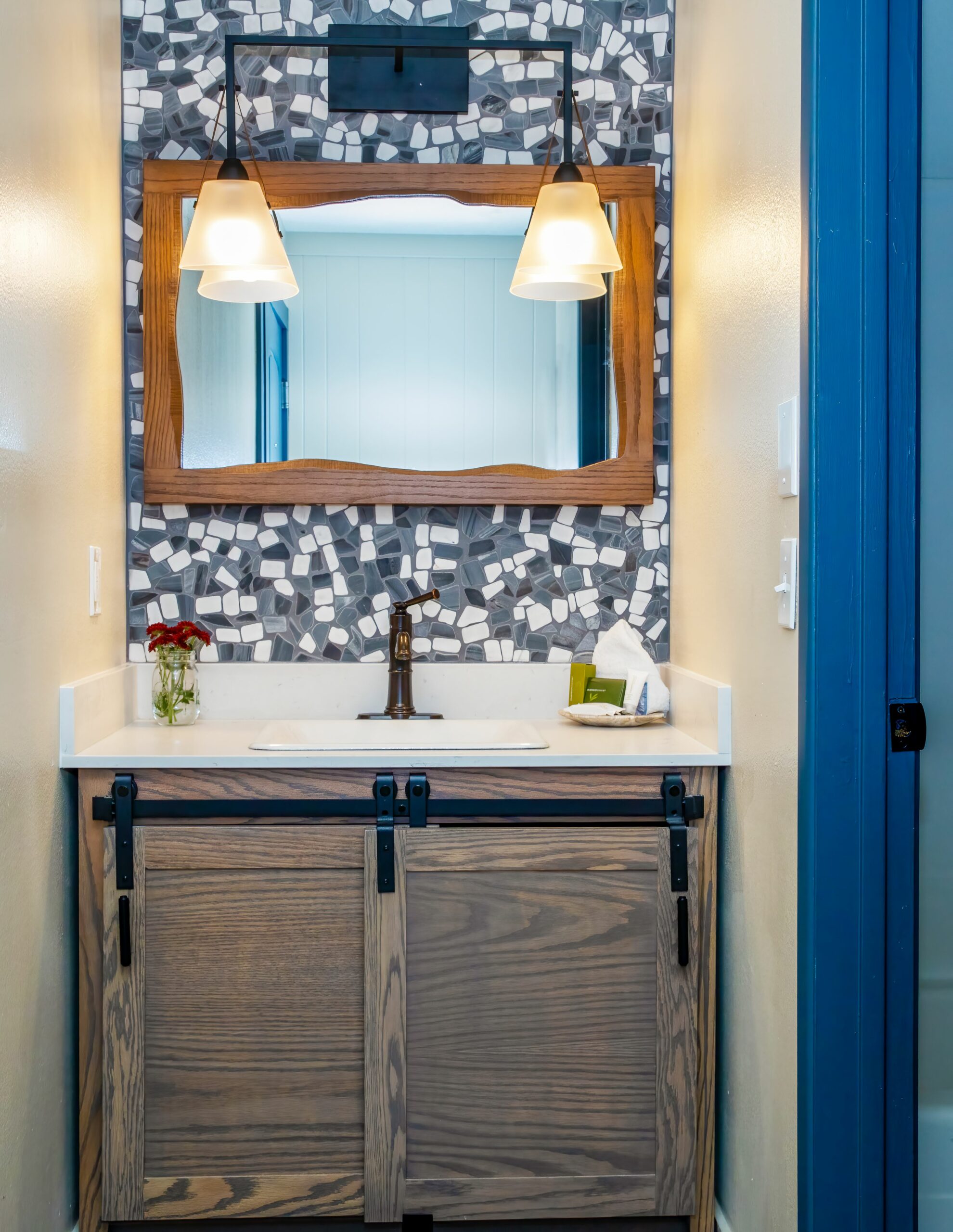 Sophisticated marble-finished bathroom, a mirror above the washbasin, adorned with stylish lighting fixtures.