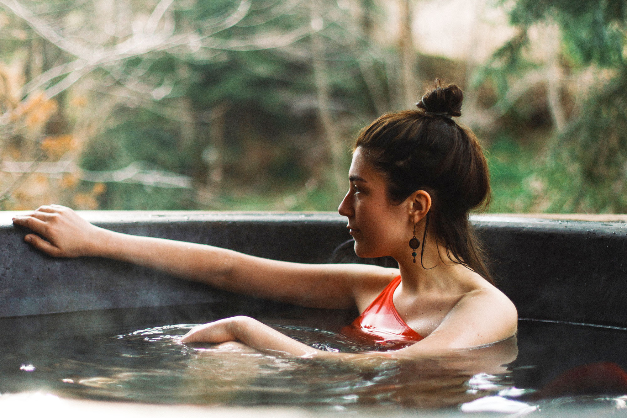 Girl in red relaxes in hot tub, savoring a serene and tranquil moment.
