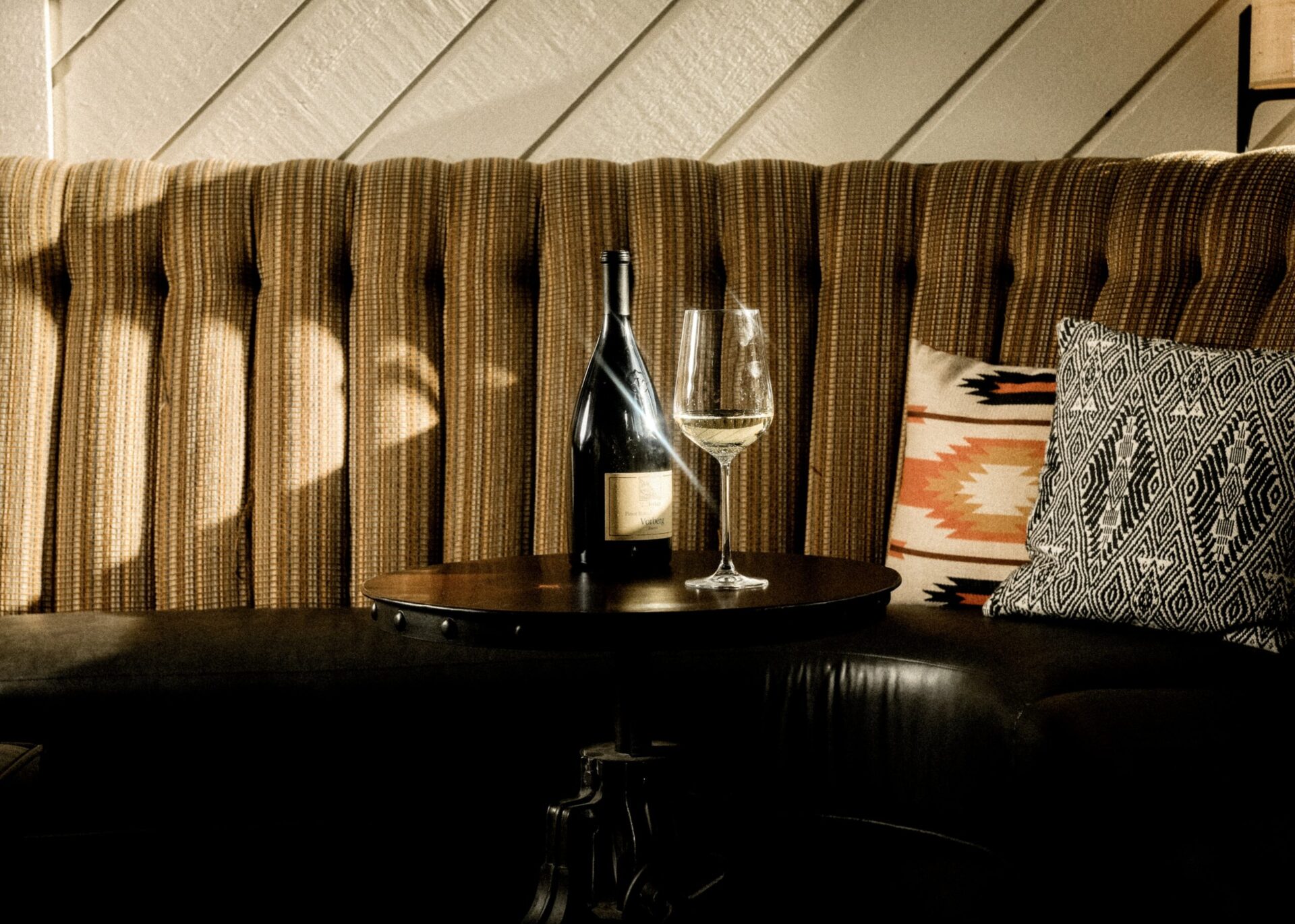 The lounge table is adorned with a black wine bottle and accompanying glass for a stylish touch.