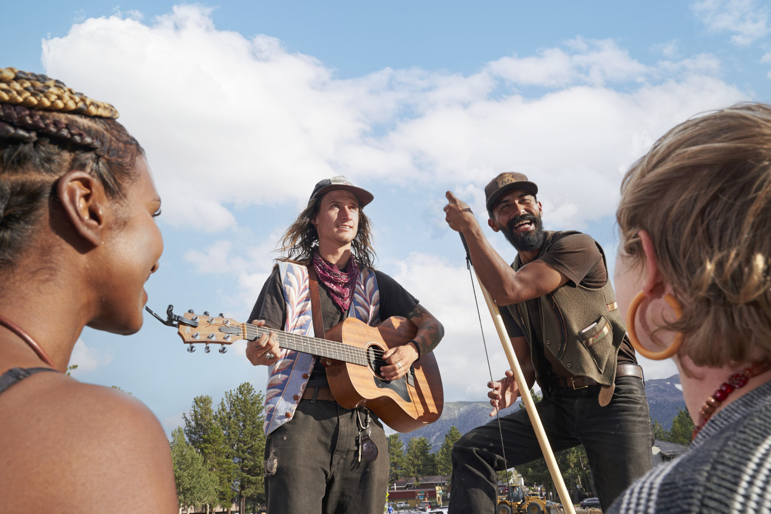 Musicians play instruments on a roadside stage, showcasing their talent to passersby.