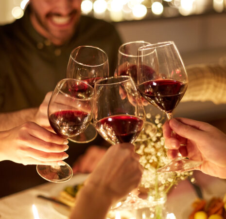 People clink wine glasses, toasting joyously amid the warm, glowing lights.