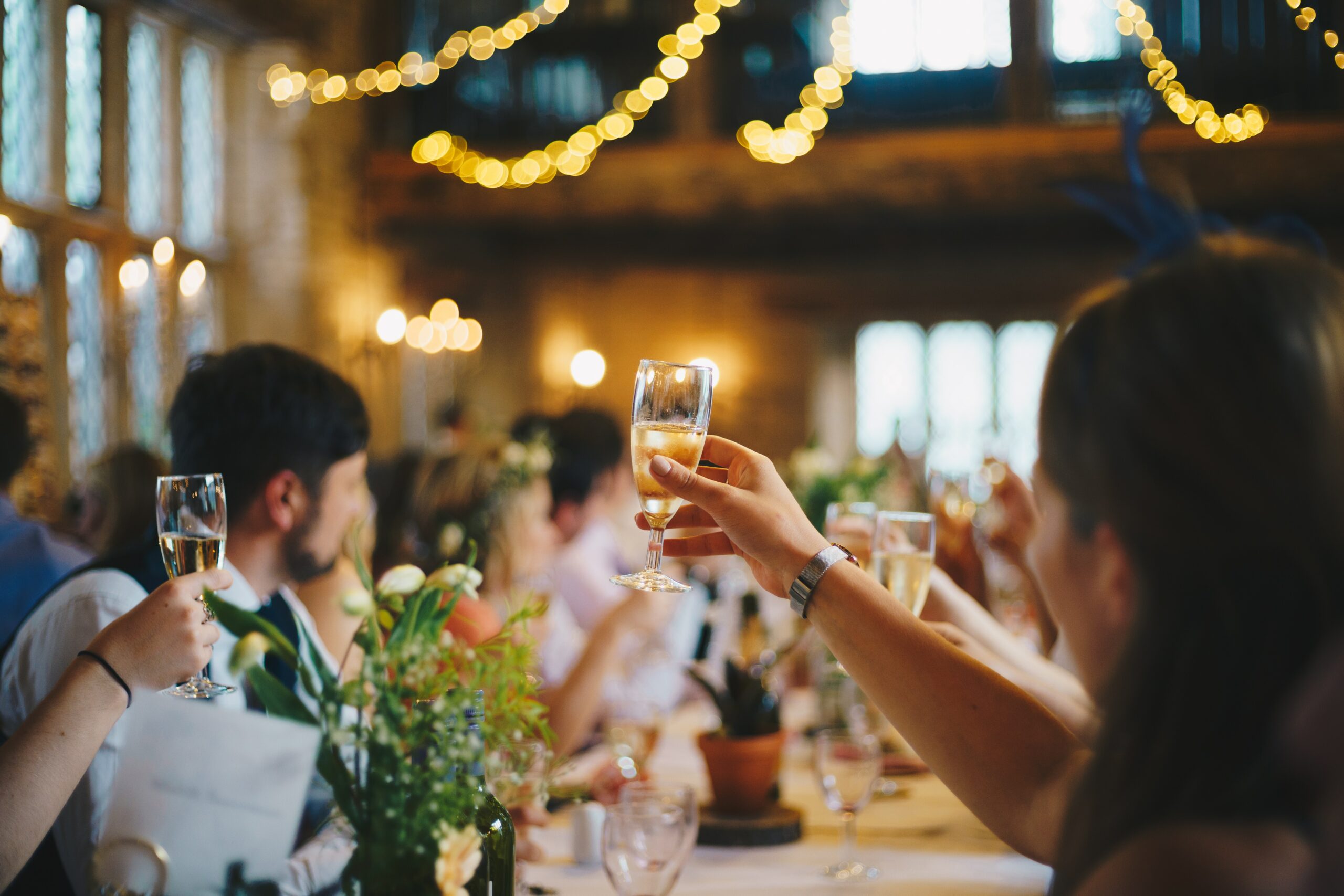 People lift their glasses in a joyful toast, celebrating a happy moment together.