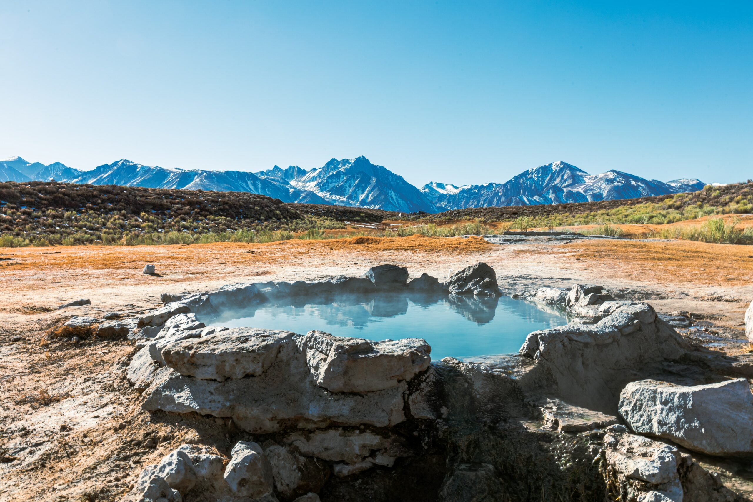 Captivating photo of a barren land with a small pond and a scenic mountain view.