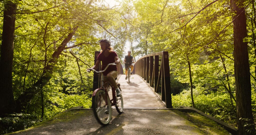 Outbound Stowe - couple riding bikes over bridge