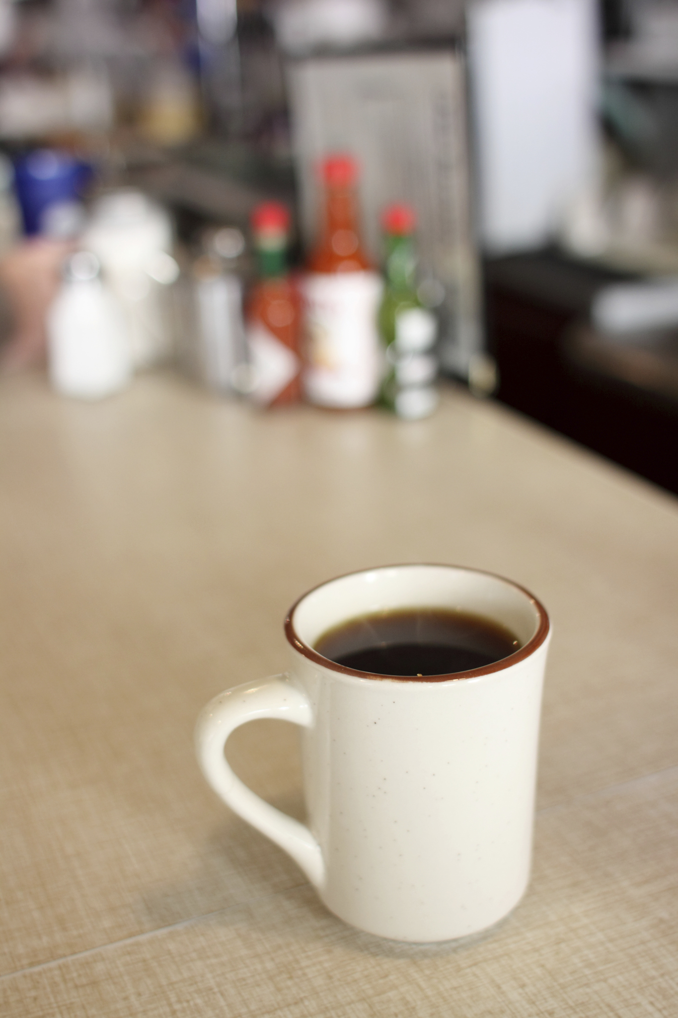 A table hosts a white coffee cup filled with the rich aroma of coffee.