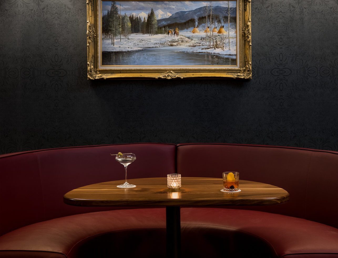 Table displays two types of drinks in distinct glasses, accompanied by a candle and landscape portrait.