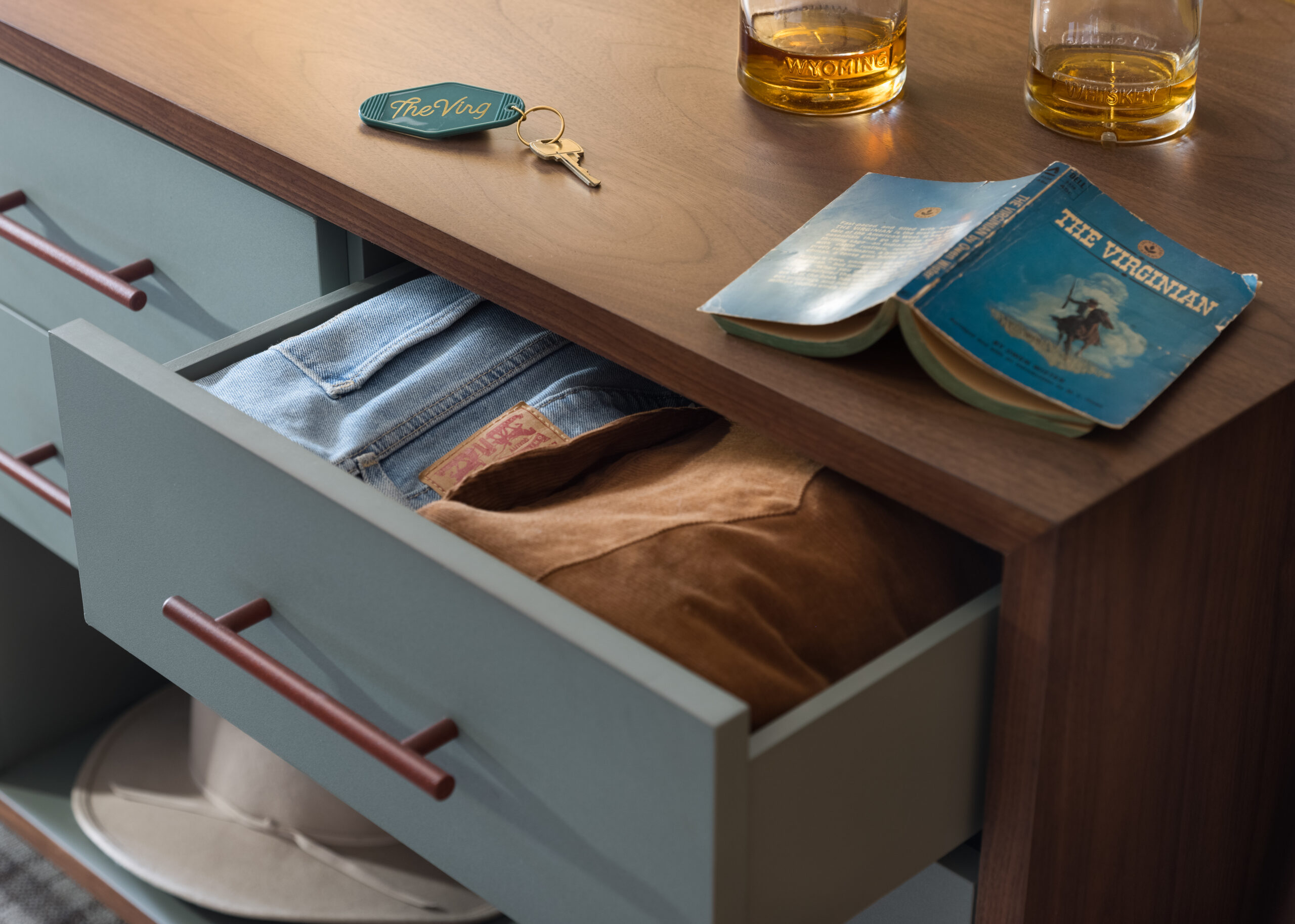 Clothes neatly stored in the drawer, a key, notebook, and two glasses of alcohol on the table.