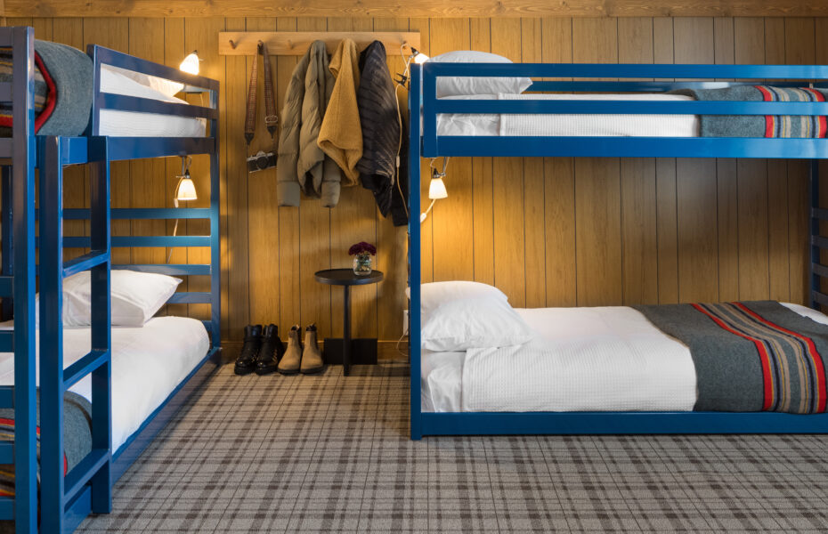 Neat bedroom with four cozy beds, well-hung clothes, and organized shoe arrangement.