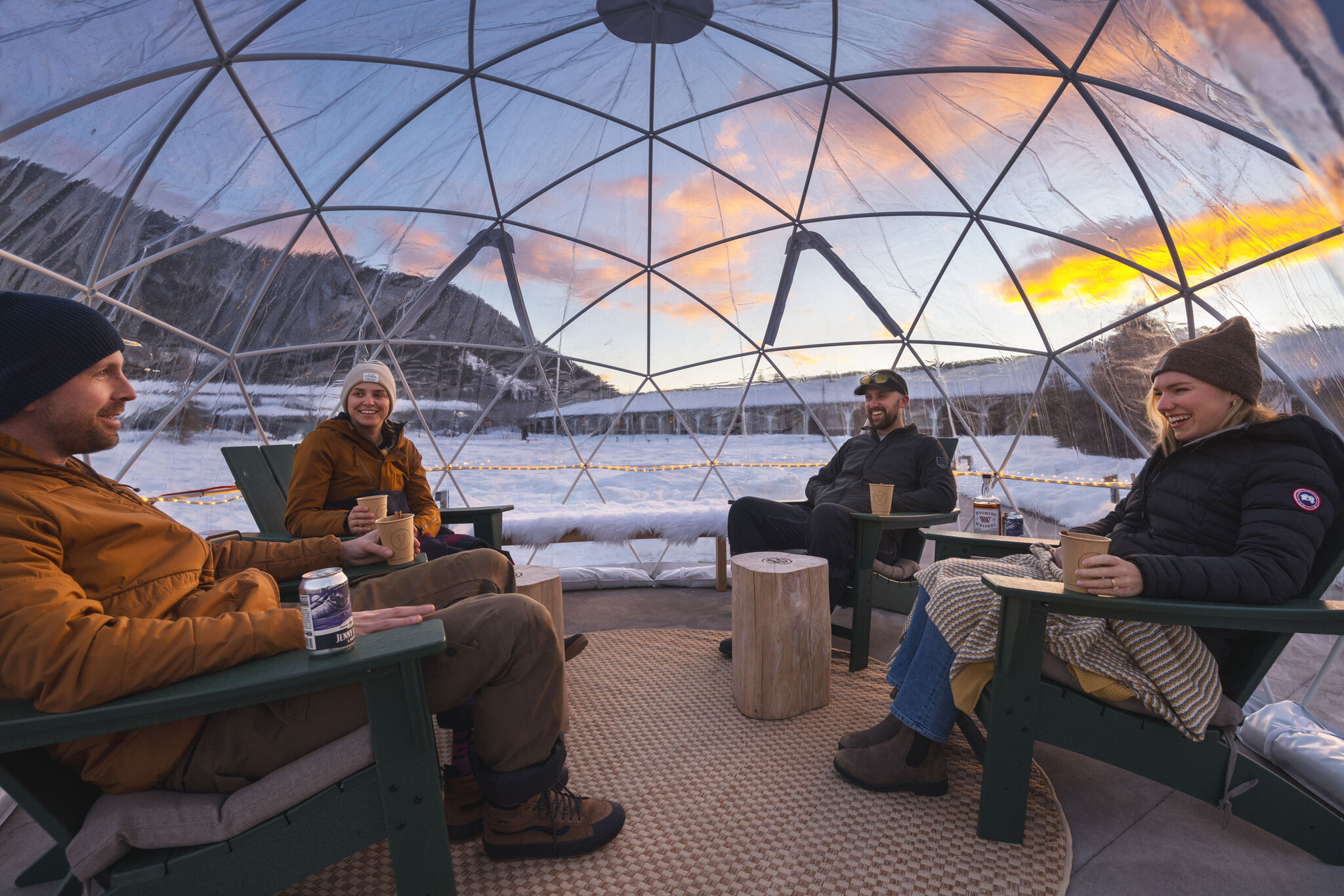 People savor beer under a transparent igloo design tent, creating a cozy and unique atmosphere.