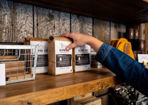 Hand arranges coffee bags on shelves, creating an organized and visually appealing display.