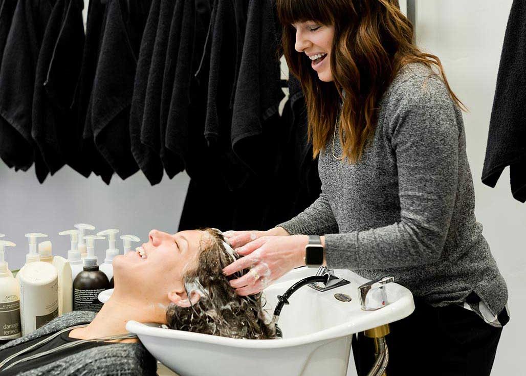 Salon stylist shampooing client's hair at the basin with focused care and expertise.