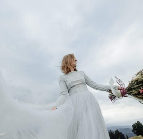 A bride in her wedding gown happily enjoys the moment, holding a flower bouquet.