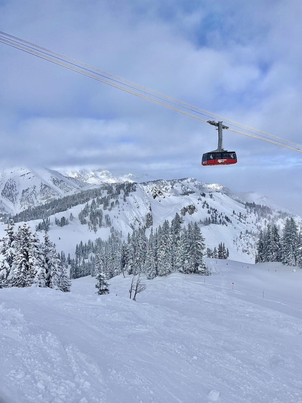 Above snowy mountains, a cable car glides, presenting a breathtaking and wondrous scenic panorama.