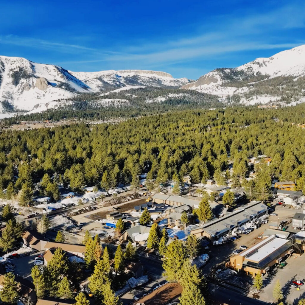 The drone-captured Mammoth exterior photo showcases stunning views of tall trees and mountains.