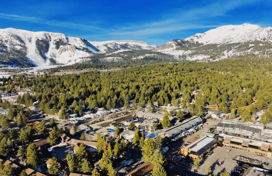 The drone-captured Mammoth exterior photo showcases stunning views of tall trees and mountains.