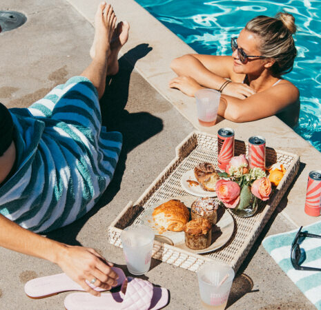 Two girls relish poolside breakfast, bathing, and sipping drinks by the swimming pool.