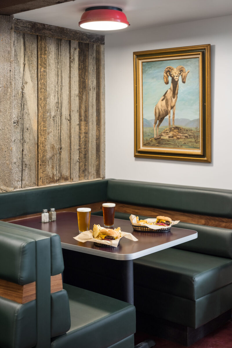 Table set with tasty meal, soft drinks, and a wall-mounted bighorn sheep portrait.