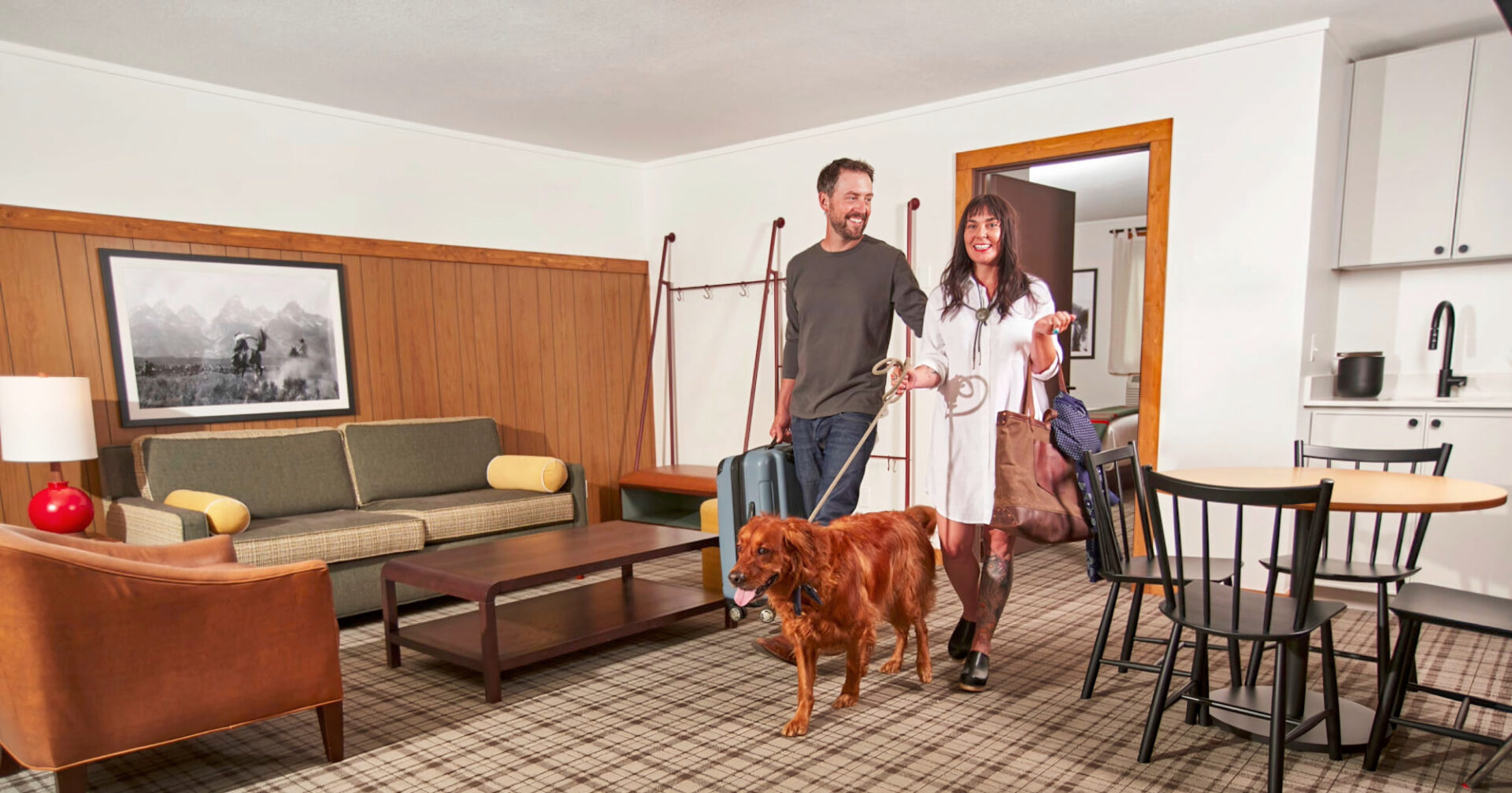 The couple enters a well-organized living space with luggage and pet, setting a welcoming tone.