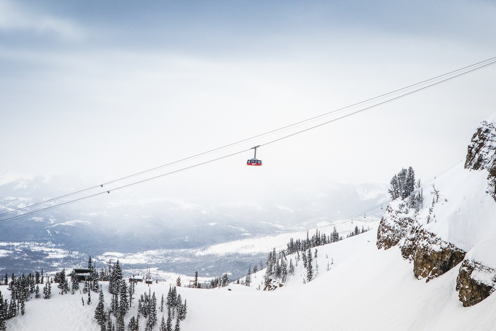 Snow-covered peaks unfold as a cable car glides, revealing a wondrous, breathtaking snowy panorama.
