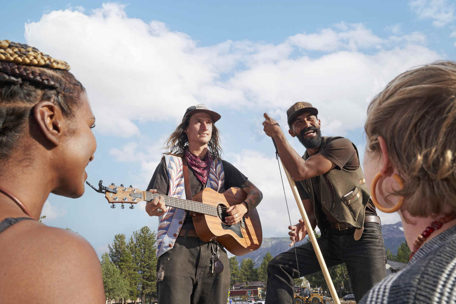 Musicians showcase talent on a roadside stage, playing instruments for passing audiences.