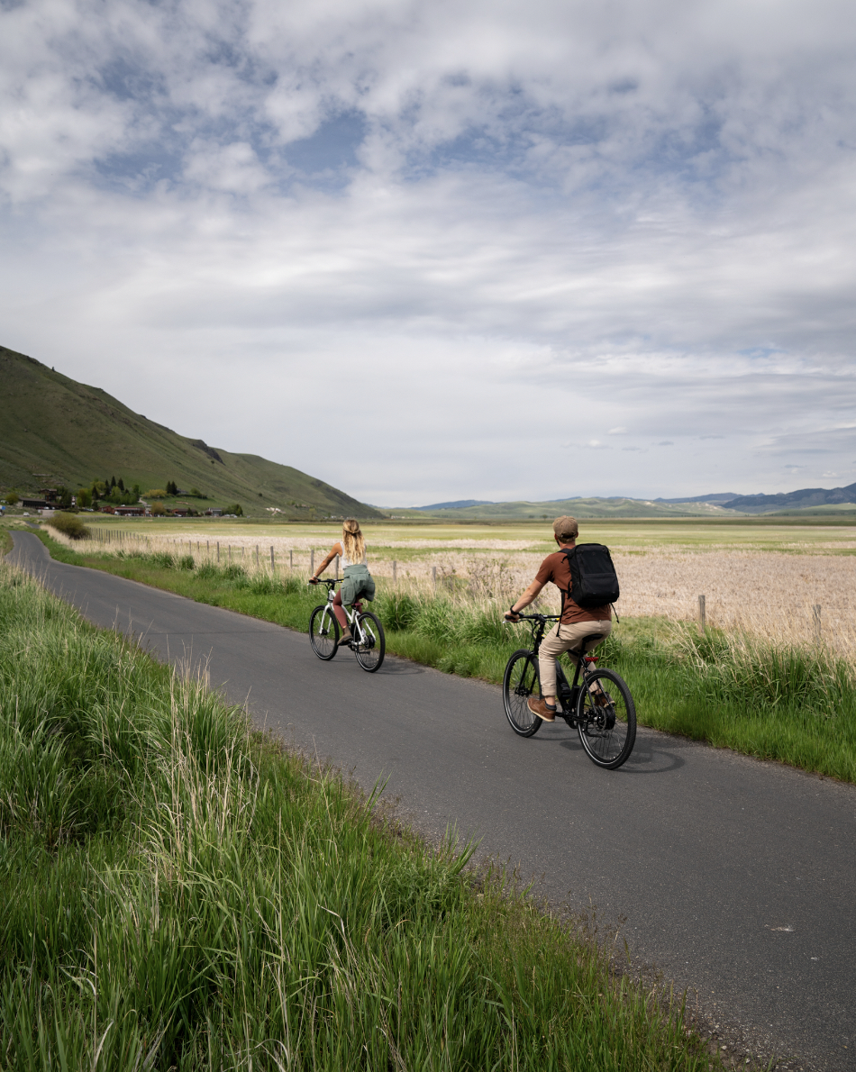 The cycling duo enjoys scenic mountain views amid lush greenery on their ride together.