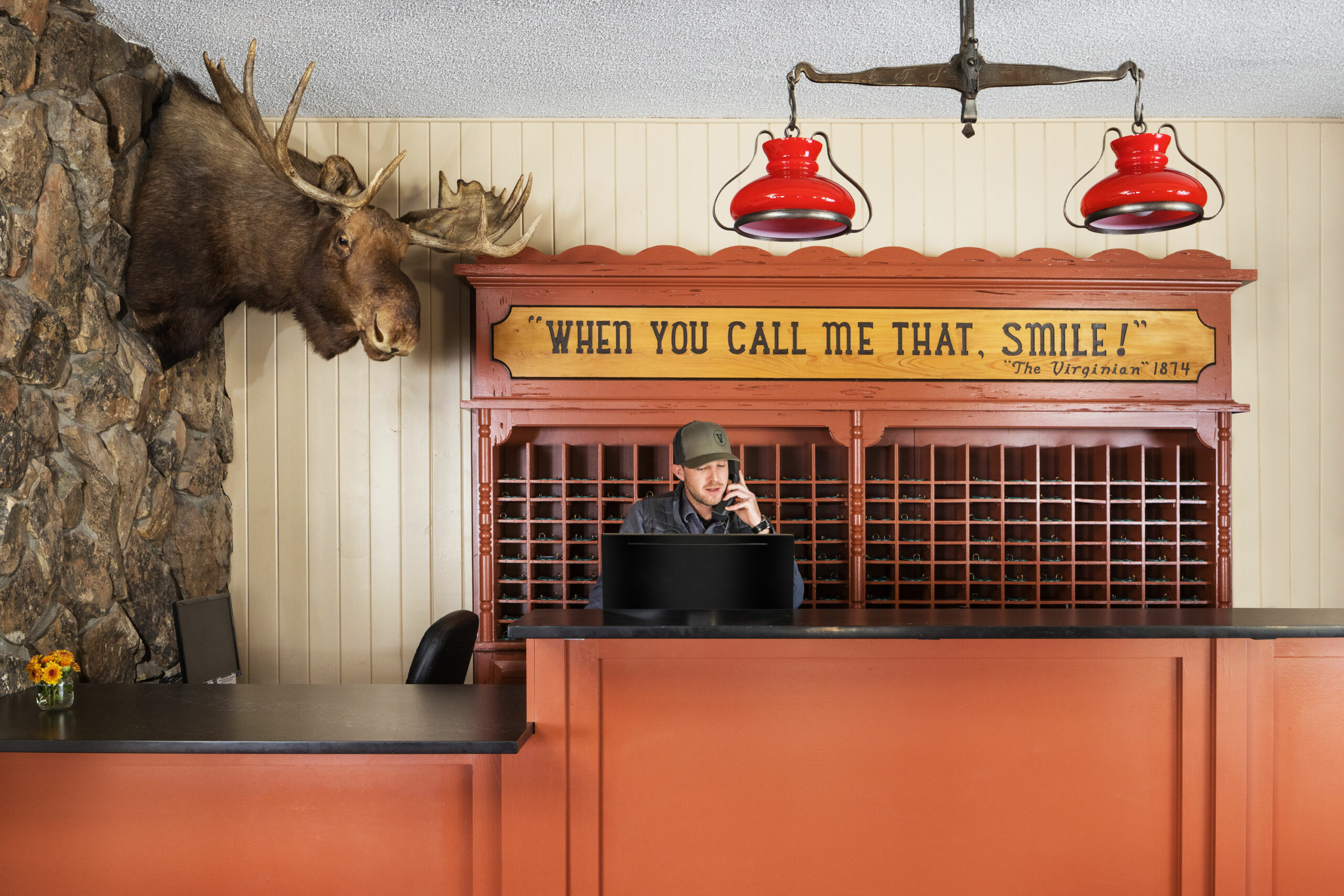 The receptionist chats on the phone near the handmade Alaska moose craft at the reception counter.
