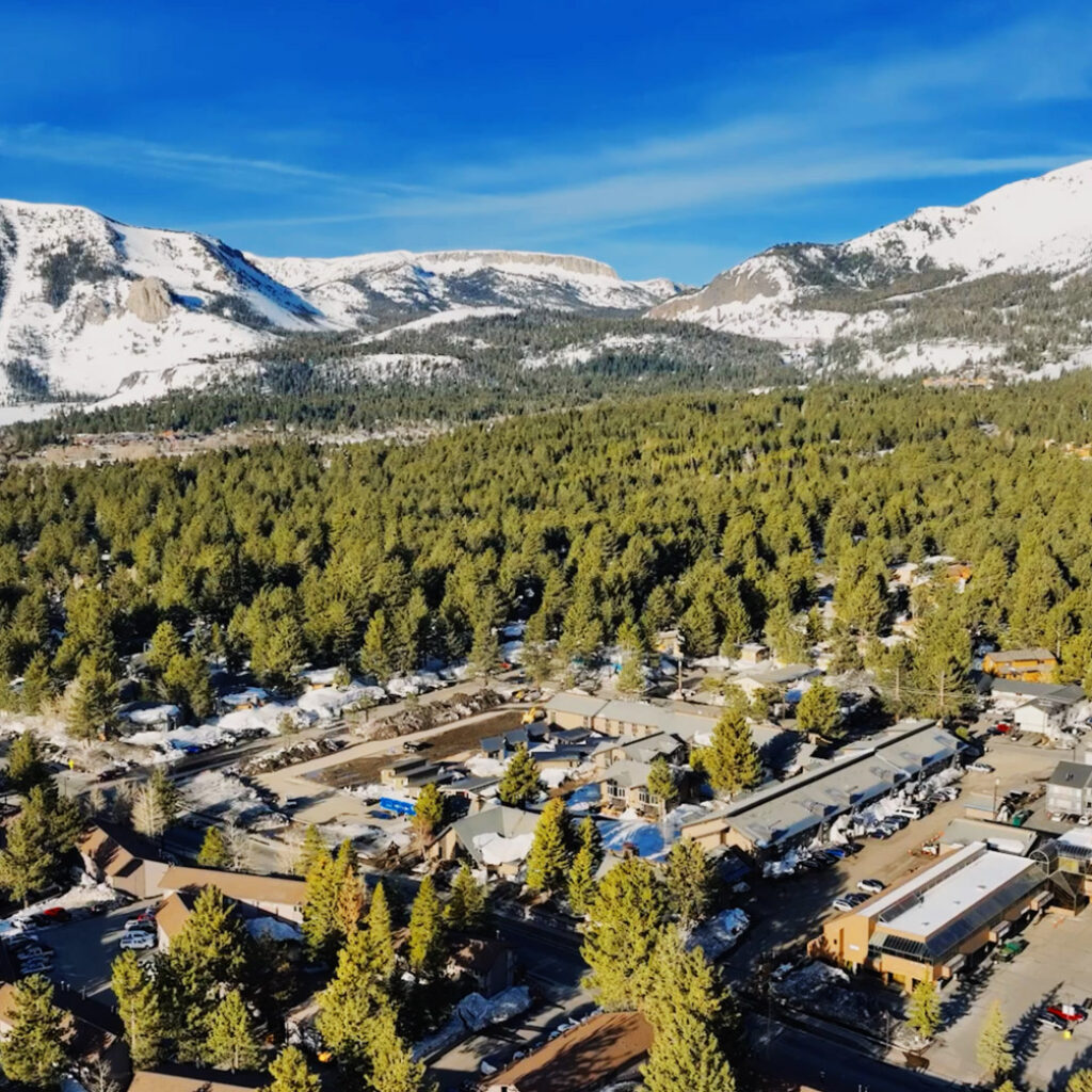Drone-captured Mammoth exterior photo reveals breathtaking tree and mountain vistas in stunning detail.