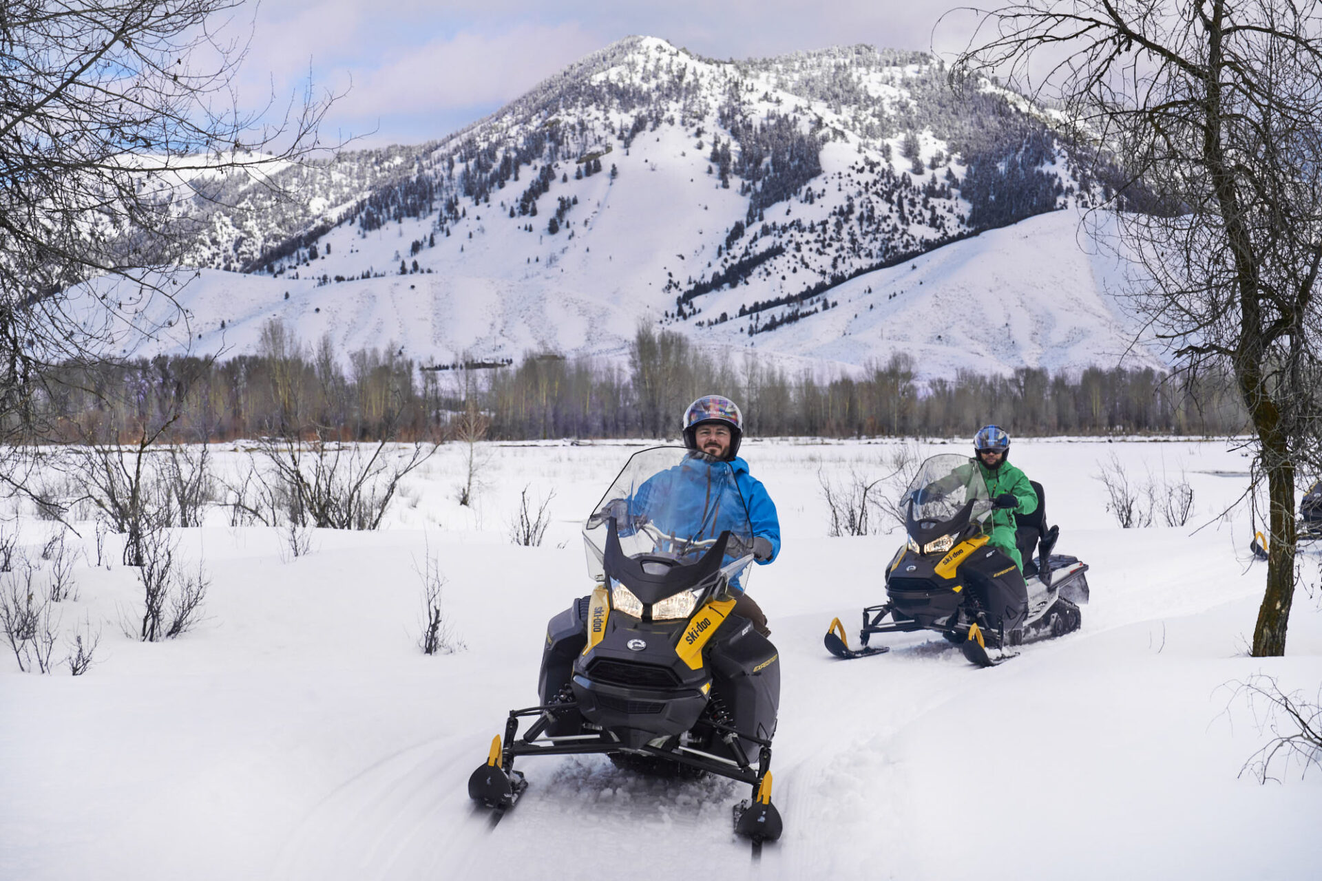 Two guests explore Jackson Hole on snowmobiles near the Virginian Lodge boutique hotel