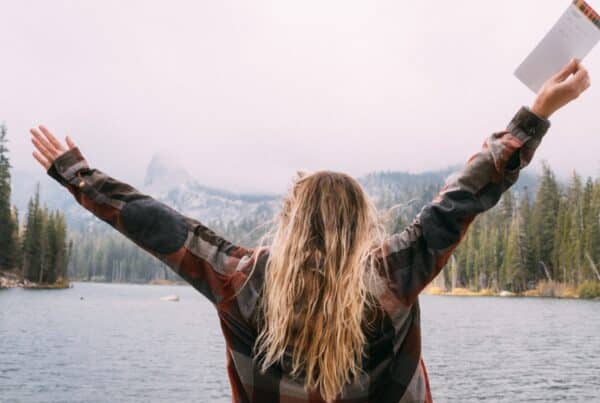 female looking at the lake arms raised