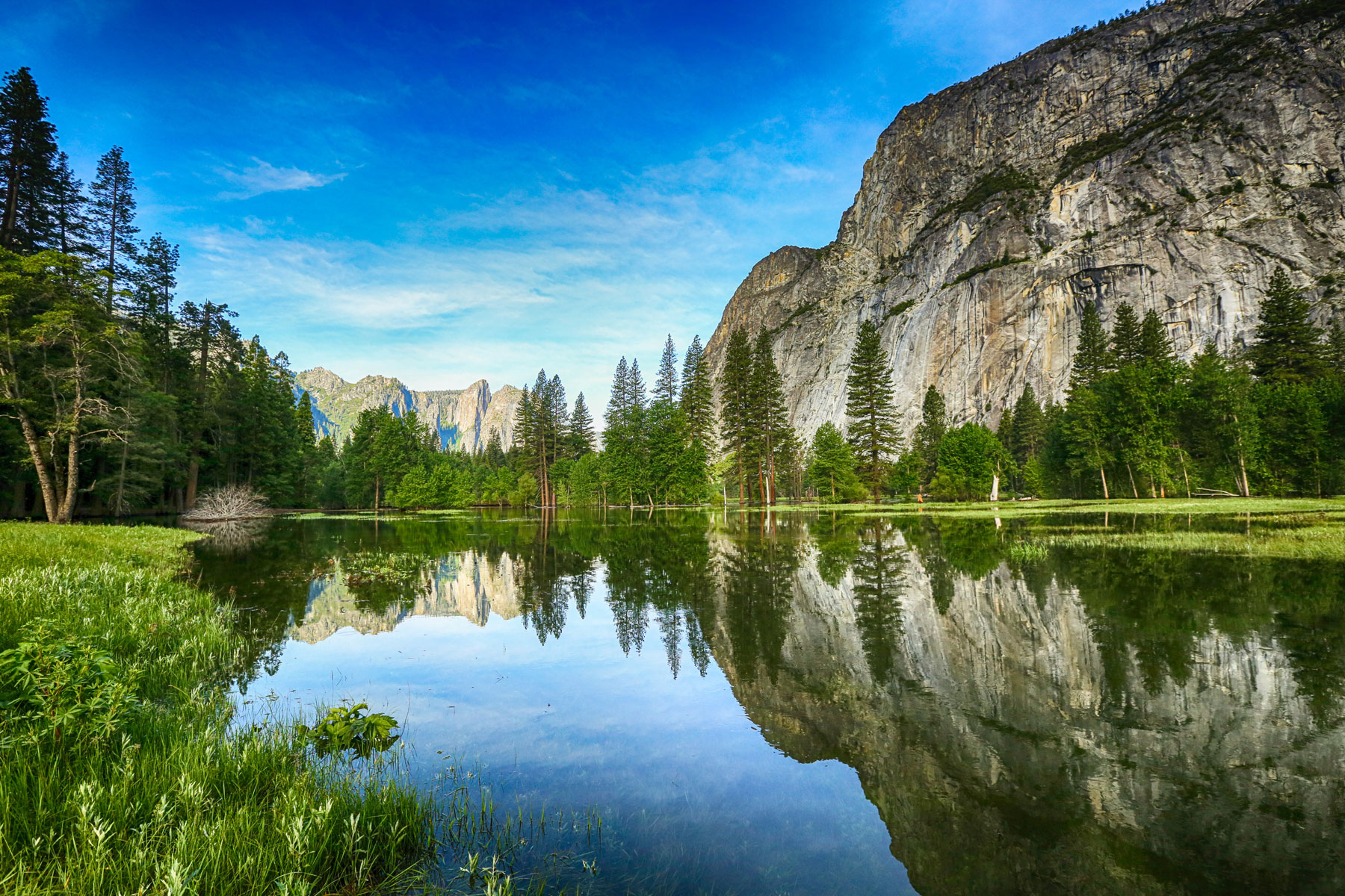 A breathtaking mountain landscape with water, lush greenery, and abundant trees epitomizes nature's splendid beauty.